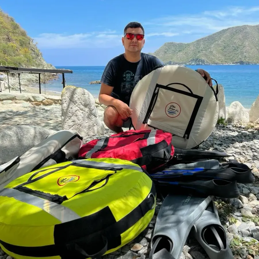 Ricardo De La Torre junto a boyas de señalización y equipo de buceo en una playa del Caribe