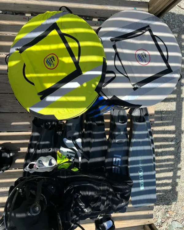 Boya amarilla y boya gris junto a aletas y equipo de buceo