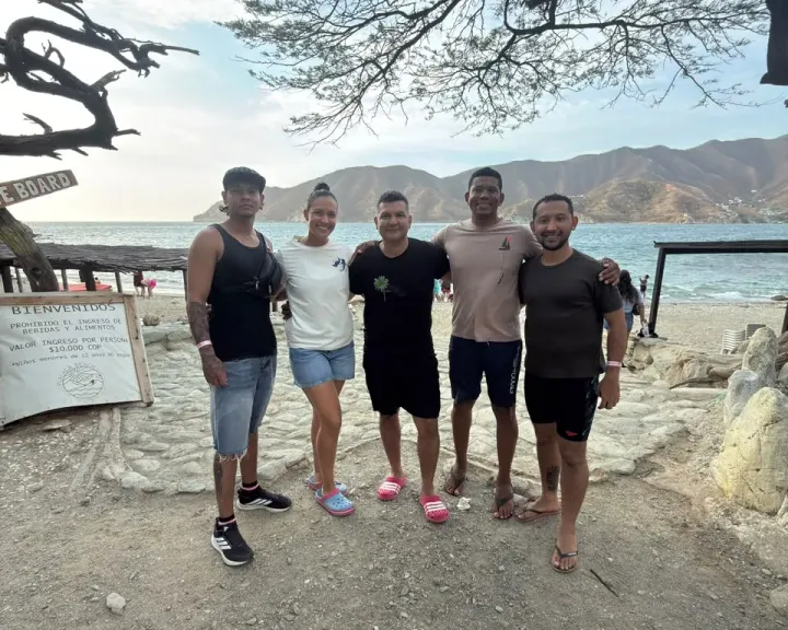 Ricardo De La Torre y cuatro integrantes del equipo y alumnos, abrazados frente al mar bajo un árbol